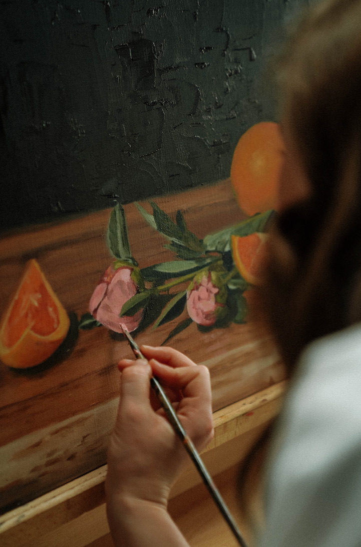 Mylie Jane Derrick painting oranges and blooms in the studio.